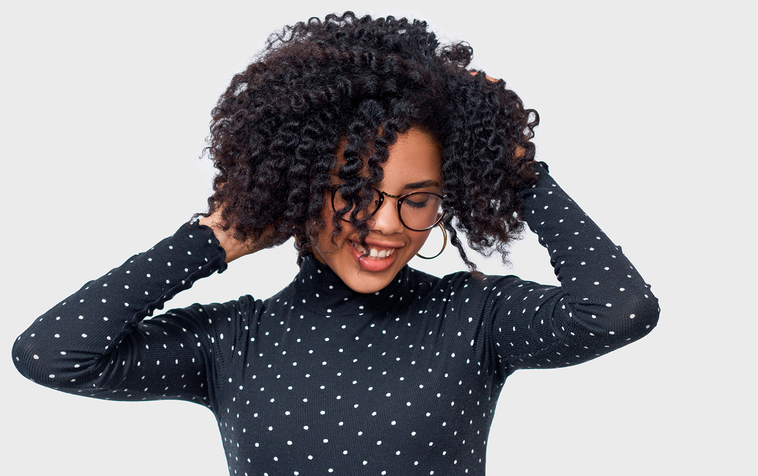 Building Better Hair African American female smiling broadly with her hands in her beautiful, healthy hair.