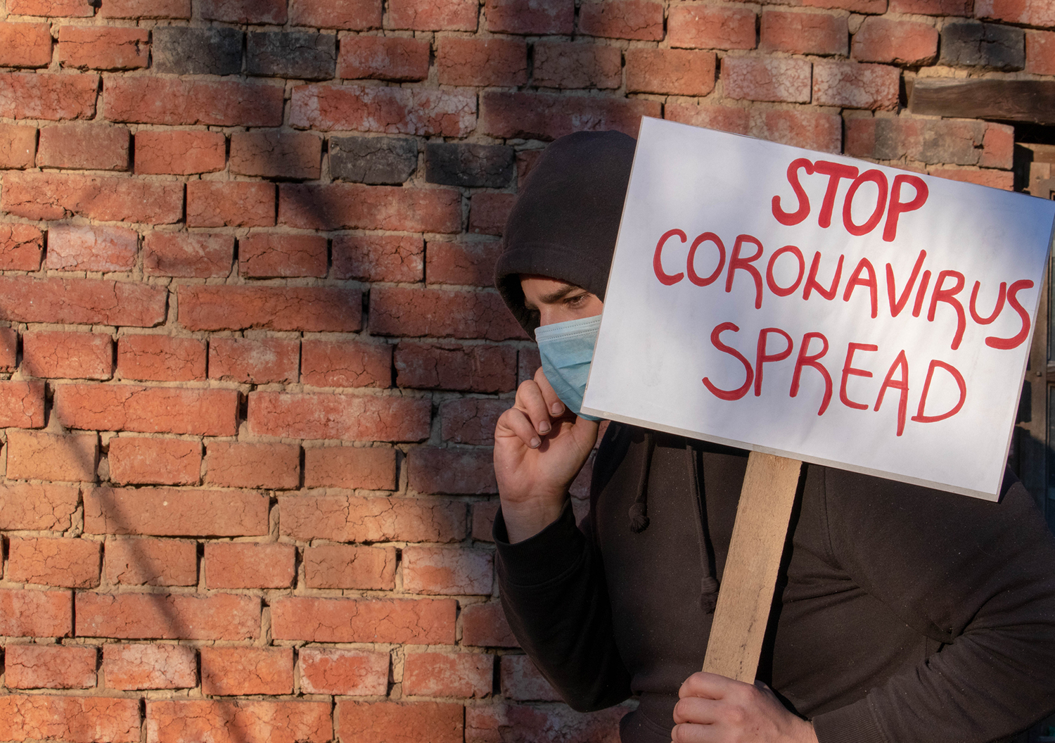 Coronavirus: How to Boost Your Immune System & Protect Yourself A man in a face mask carrying a sign that reads stop coronavirus spread.