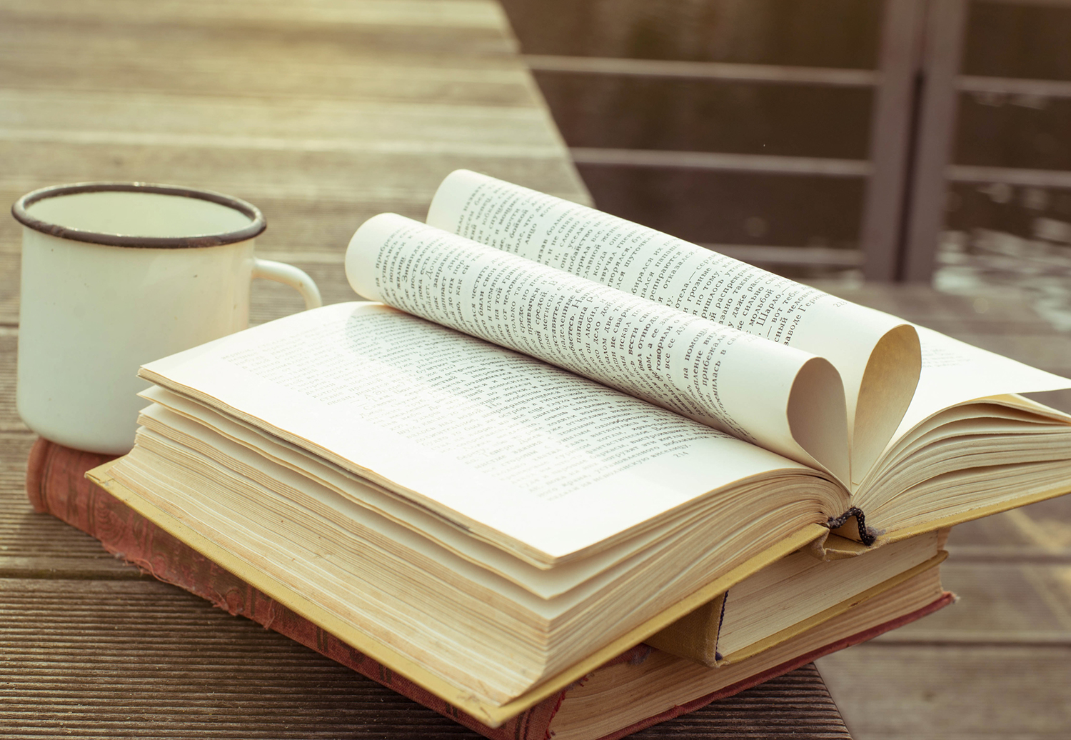 Opened vintage book on the wooden table with old fashioned cup of tea.
