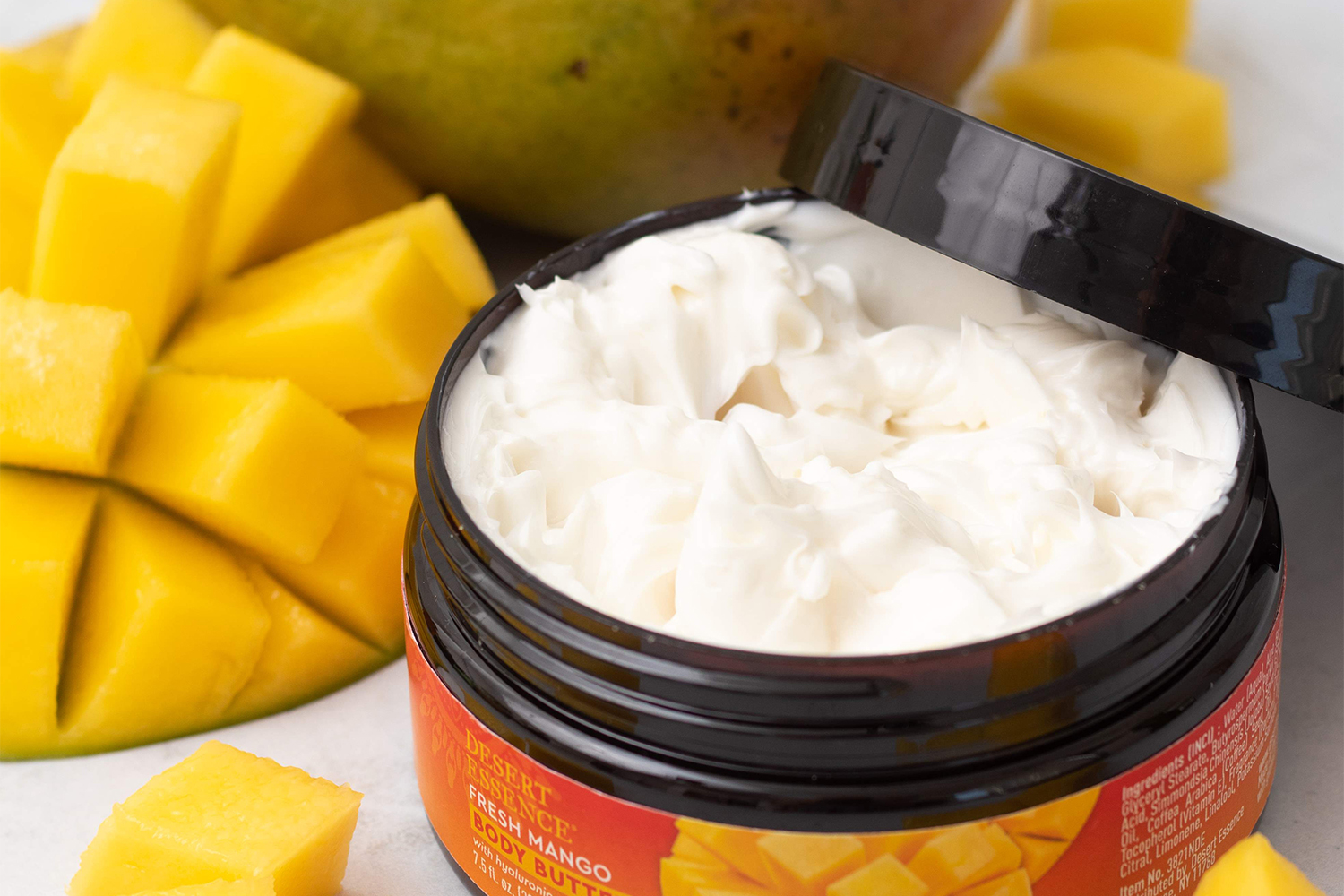 Desert Essence Fresh Mango Body Butter a small jar of lotion and some fresh mangoes