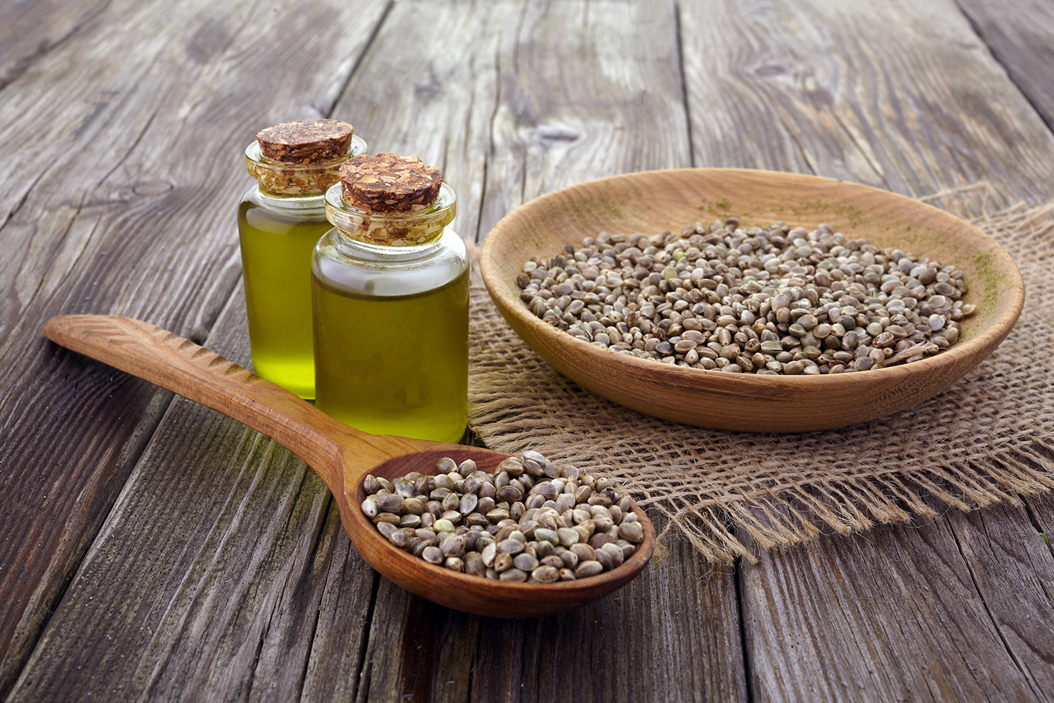 a bowl of hemp seeds and vials of oil