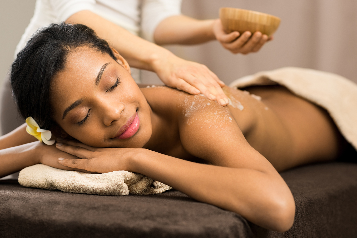 a relaxed woman having a scrub applied to her skin