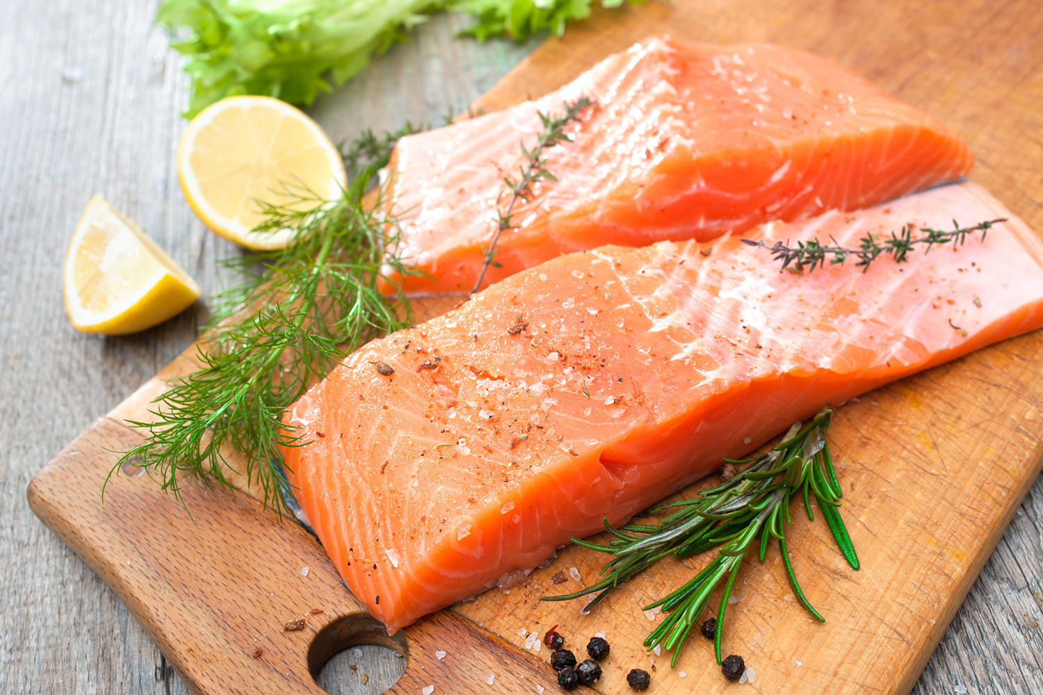 salmon on a cutting board with rosemary and lemon