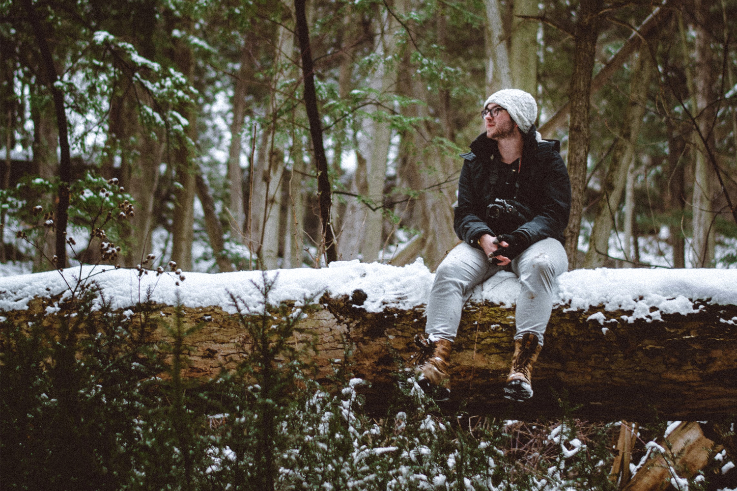 a man sitting on a fallen tree across a shallow gorge