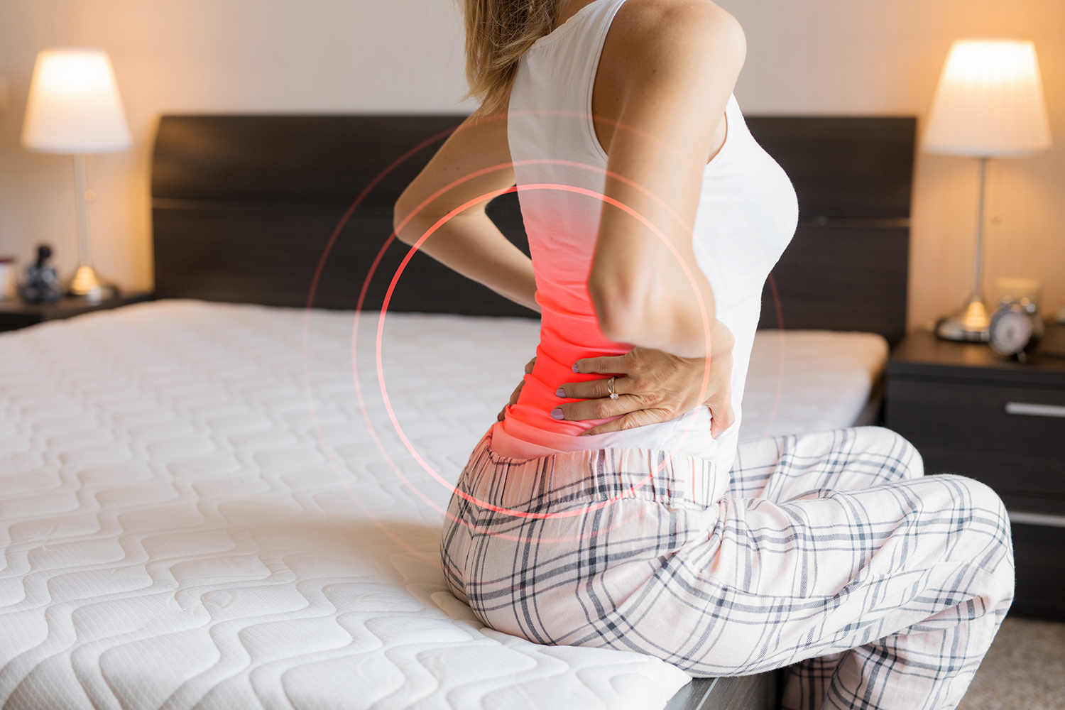 a woman getting out of bed but her back already hurts