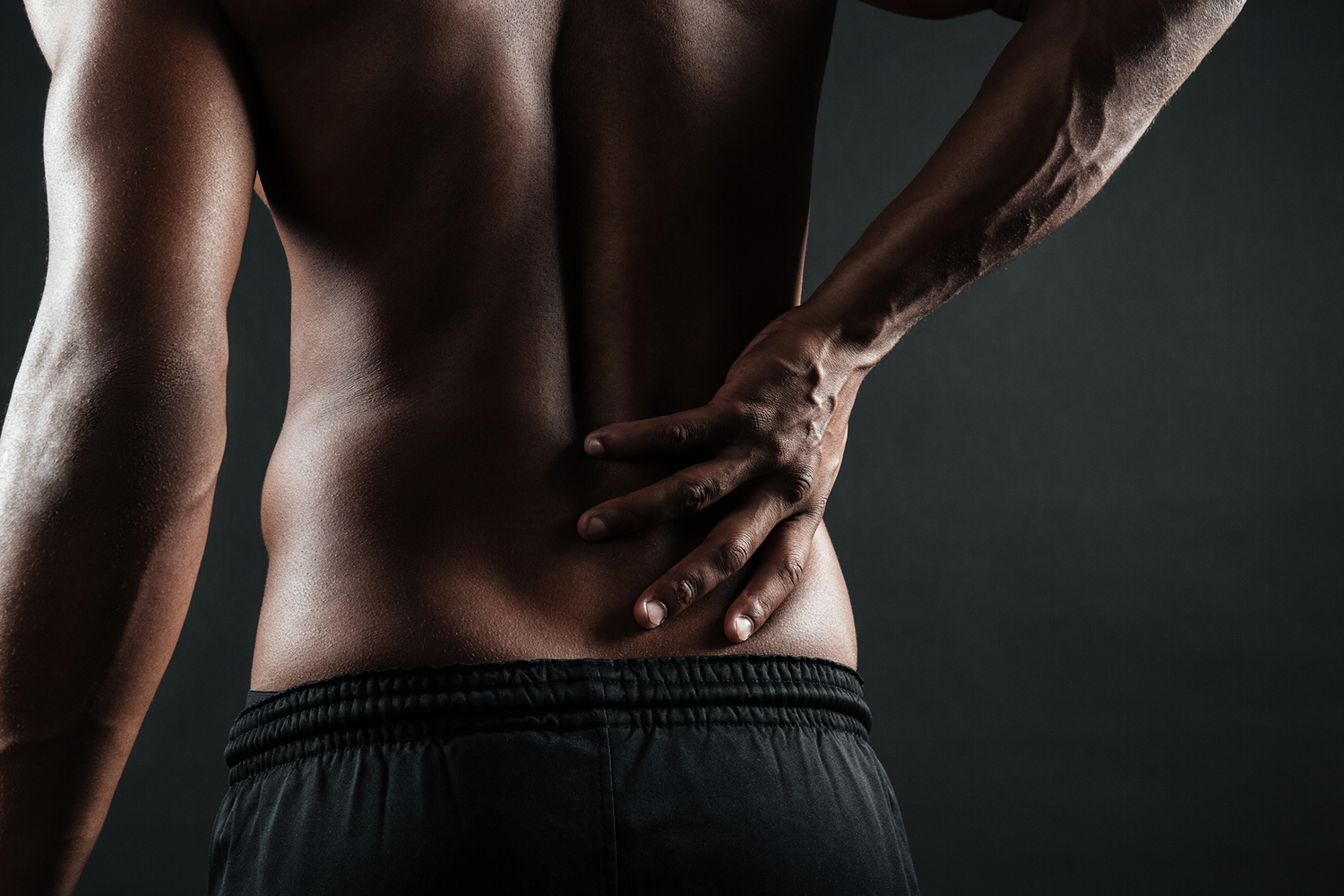 View of a man from the back, holding his back with fibromyalgia pain.