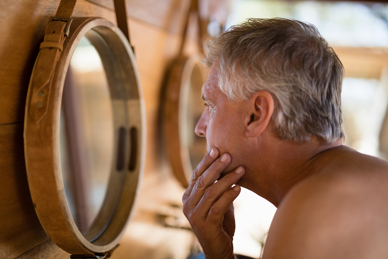 an older man with gray hair and wrinkles looking in the mirror