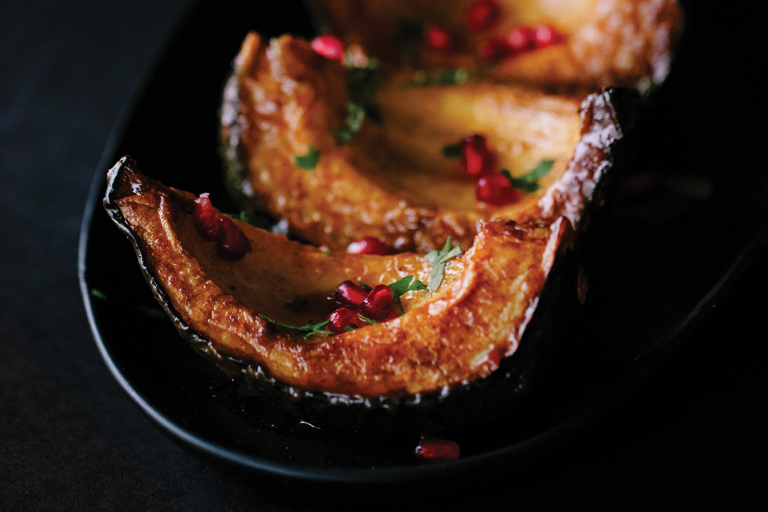 Spice-Drizzled Acorn Squash Spice-Drizzled Acorn Squash served on a black platter with a black background.