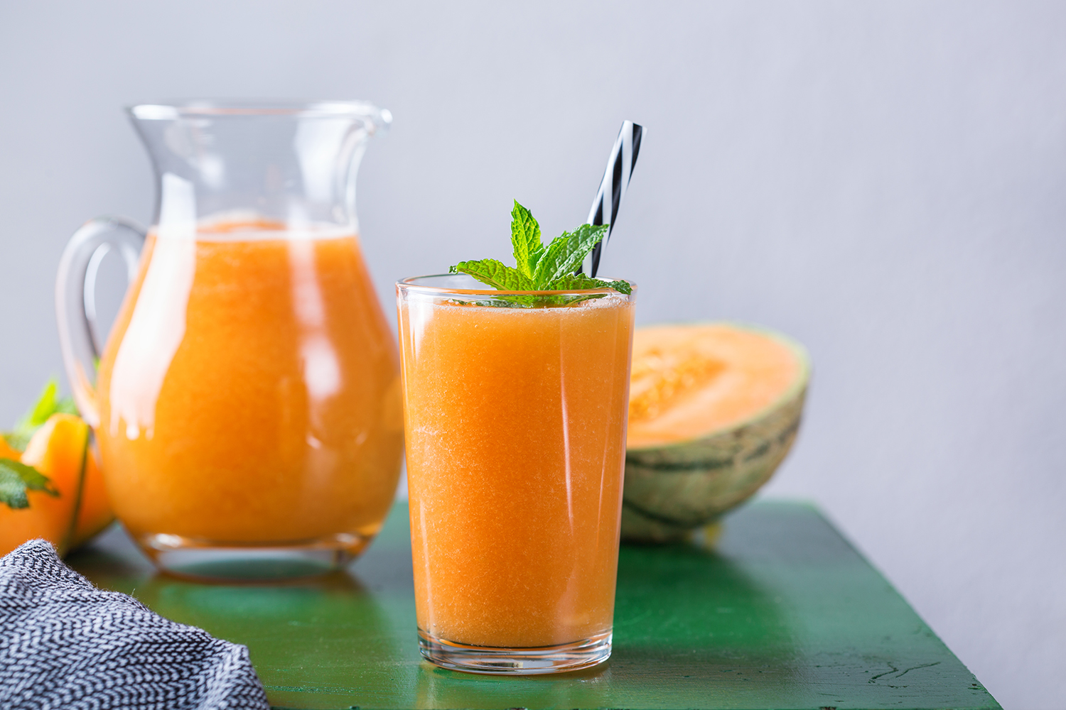 a glass of melon smoothie and slices of cantaloupe