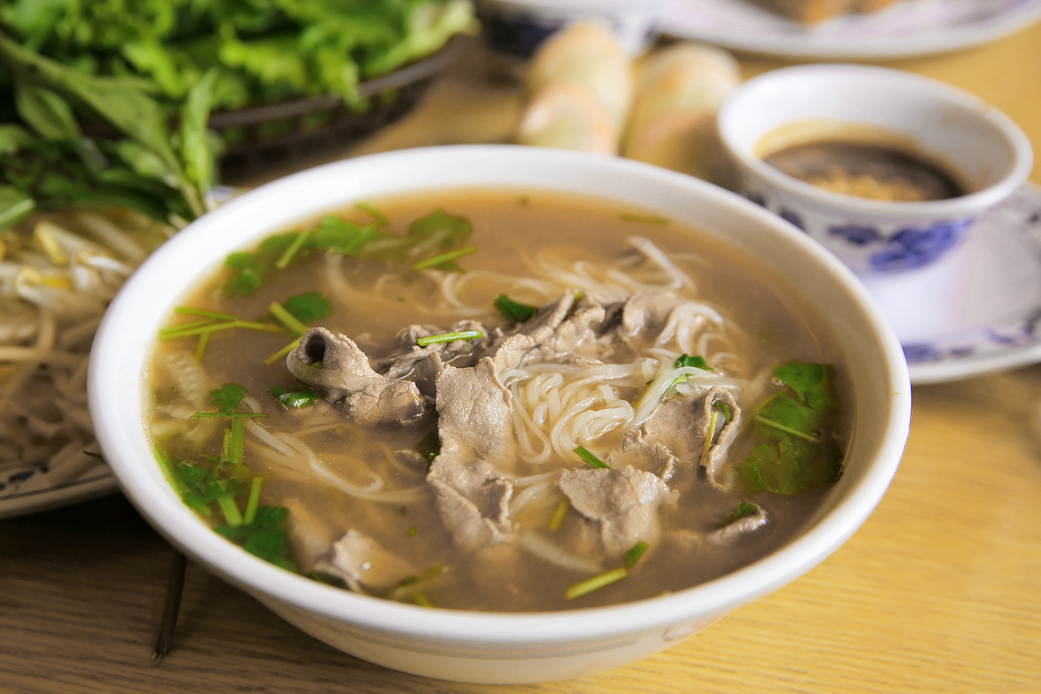 Monkfish Phở a bowl of soup with monkfish, noodles, and greens
