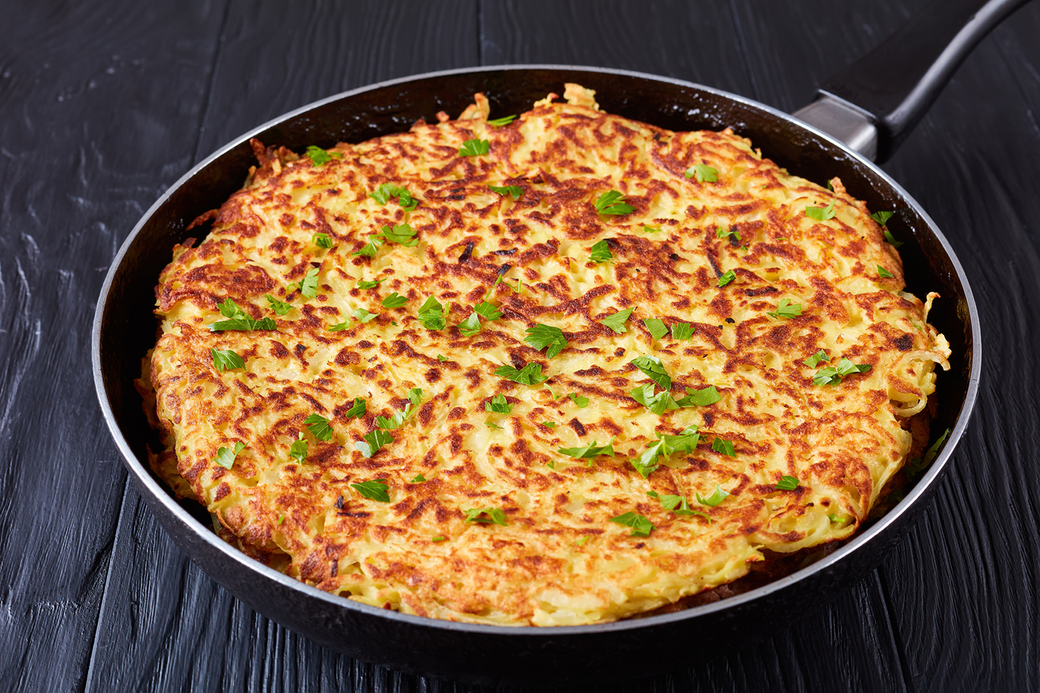 potato pancakes cooking in the pan with greens