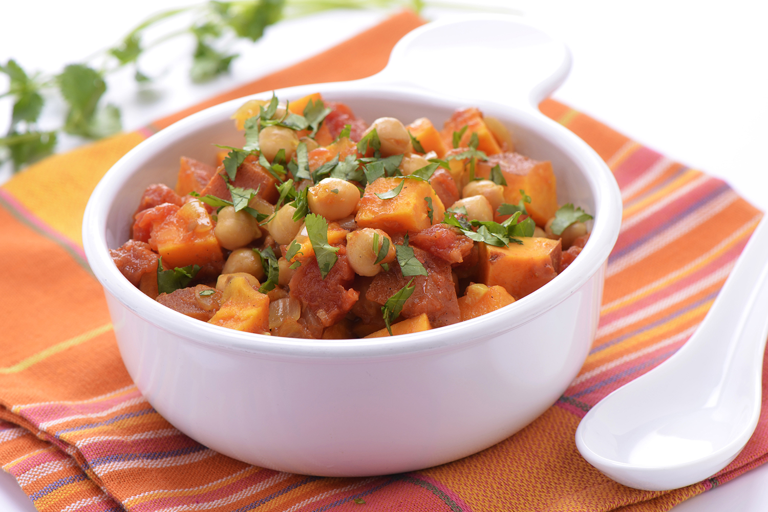 Sweet Potato-Coconut Curry with Chickpeas and Spinach a bowl of curry full of sweet potatoes, chickpeas, and greens