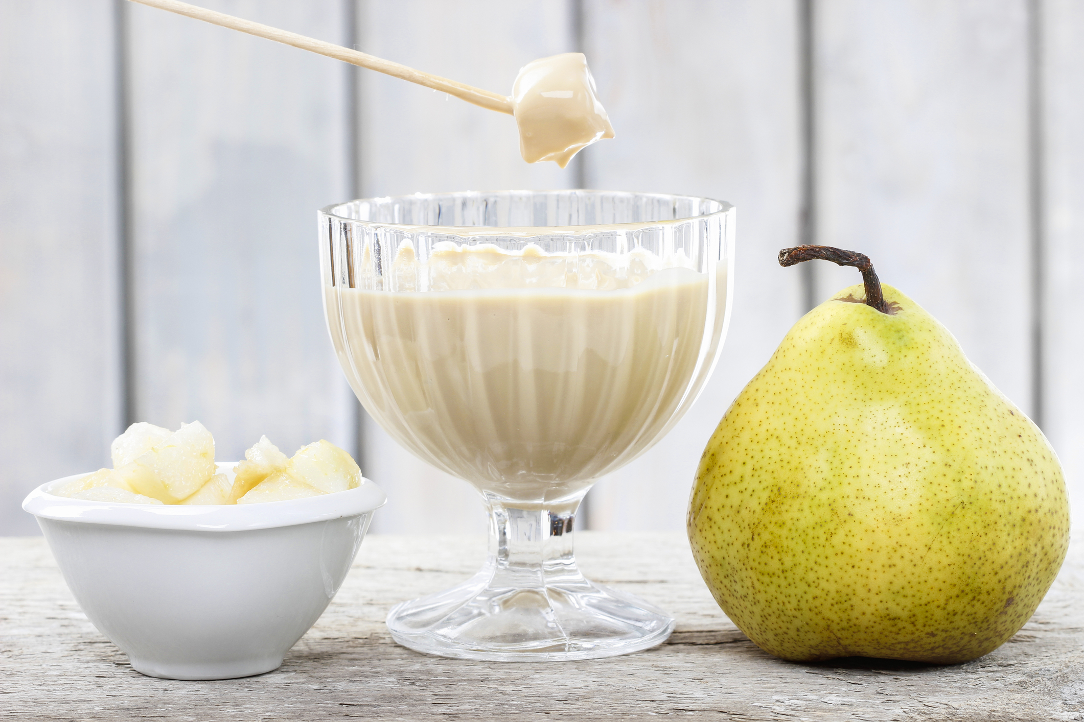 Chunks of pear being dipped into Cinnamon Cheesecake Fondue. 