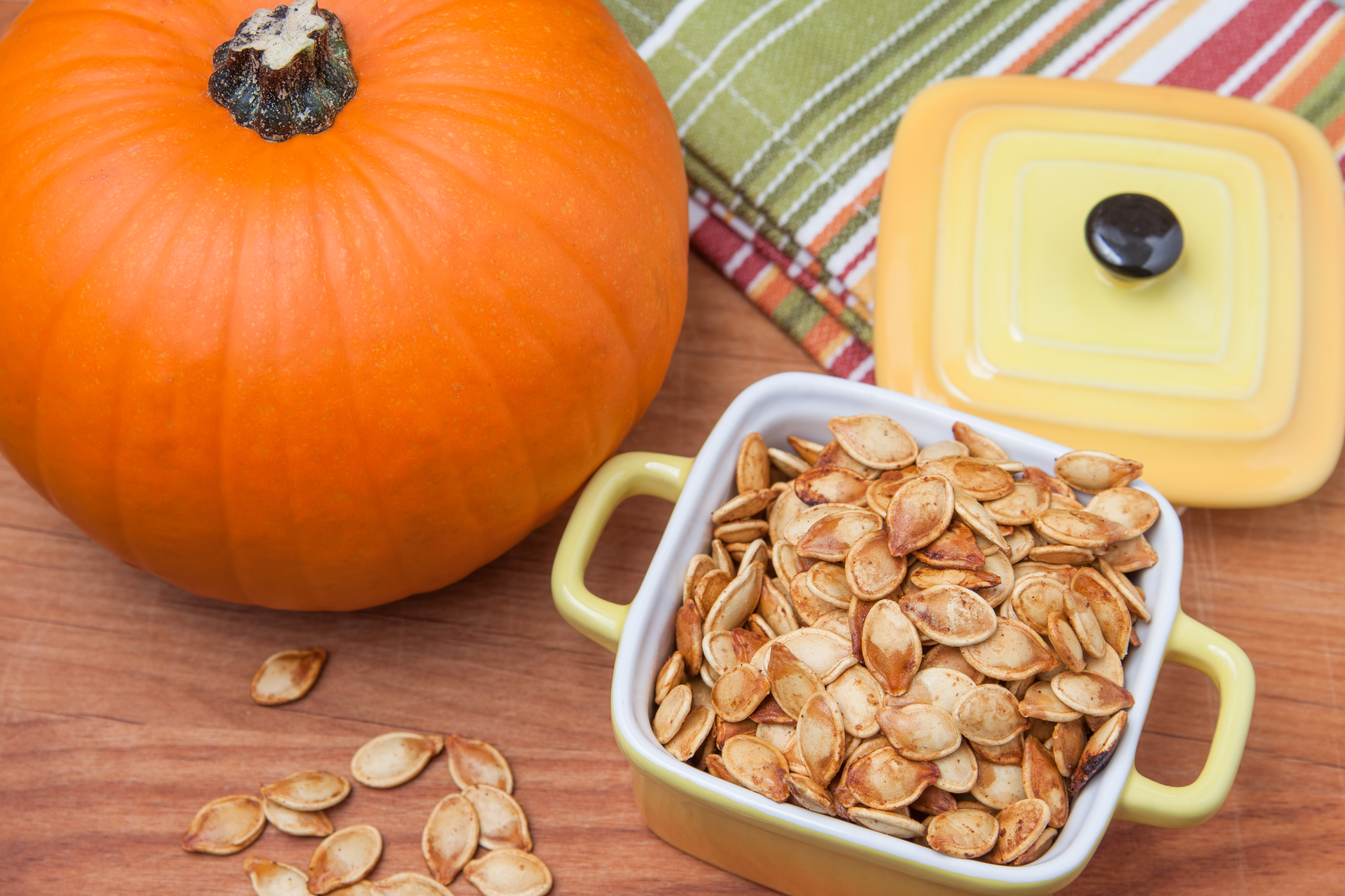 Roasted Pumpkin Seeds Roasted pumpkin seeds in a container next to a pumpkin.