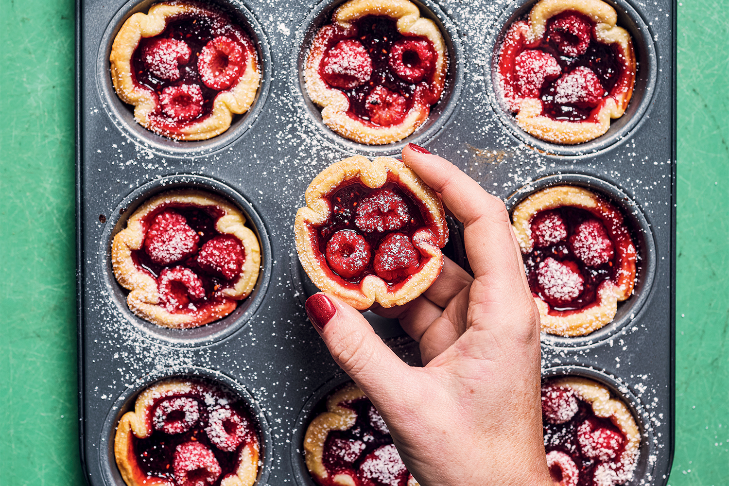 Wonky Fruit Tarts a woman removing raspberry tarts from a cupcake tin