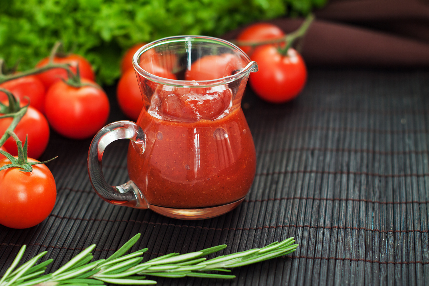Homemade Ketchup a pitcher of fresh ketchup surrounded by tomatoes