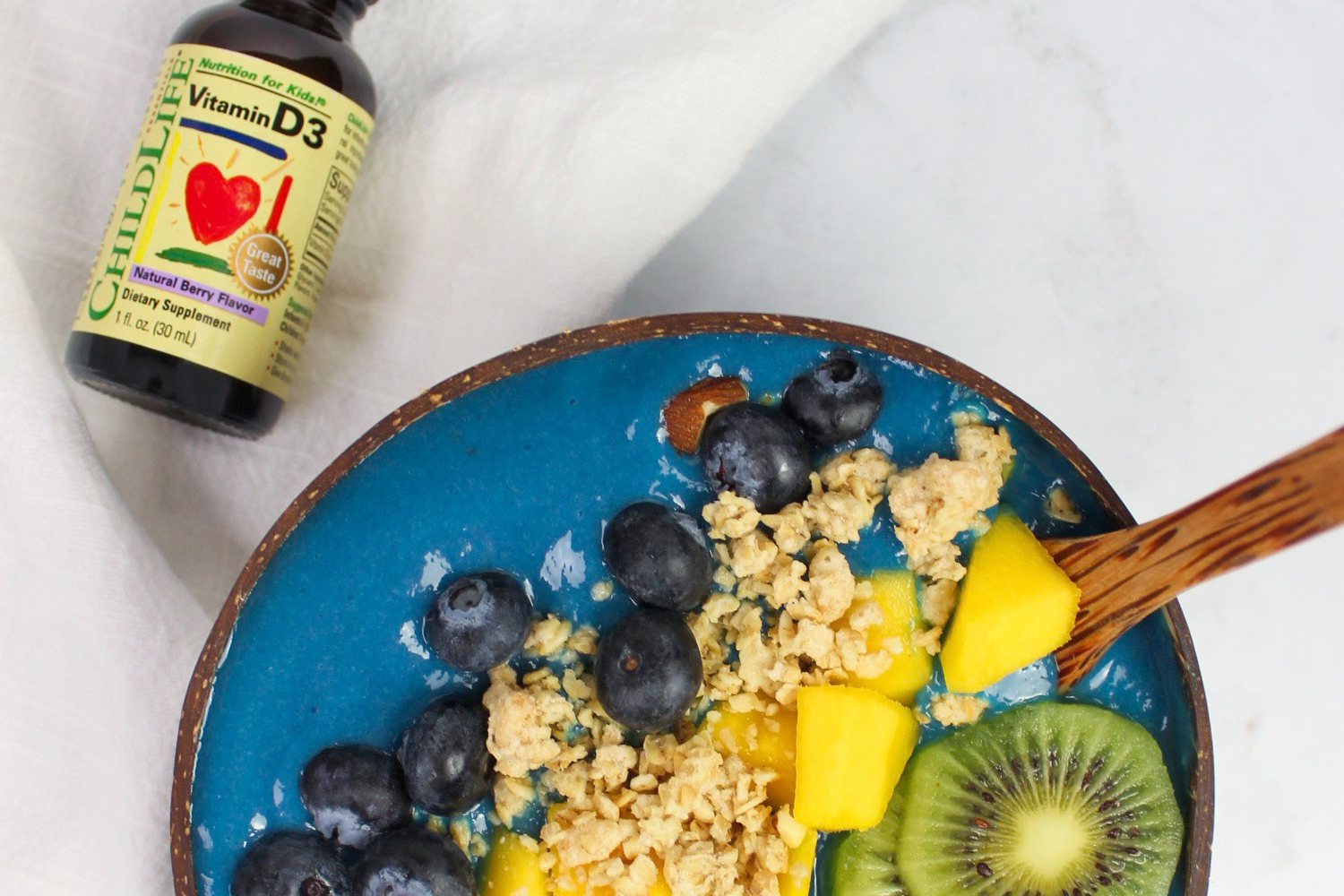 Tropical Blue Smoothie Bowl a plate of fruit and a vial of vitamins