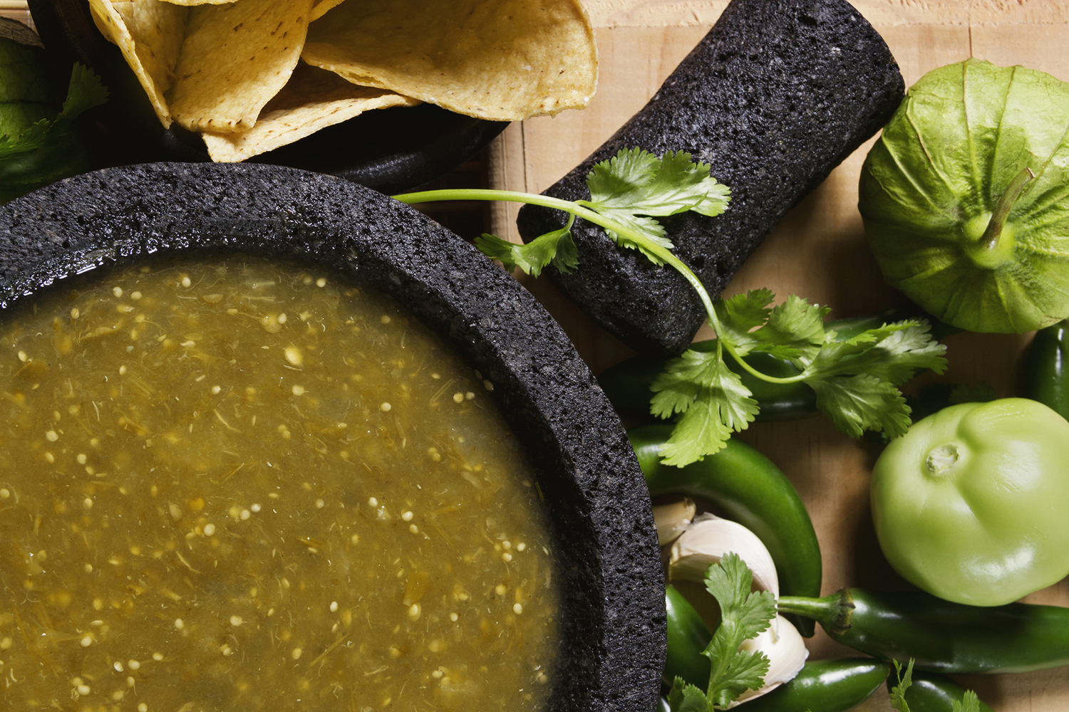 a bowl of salsa and some fresh tomatillos