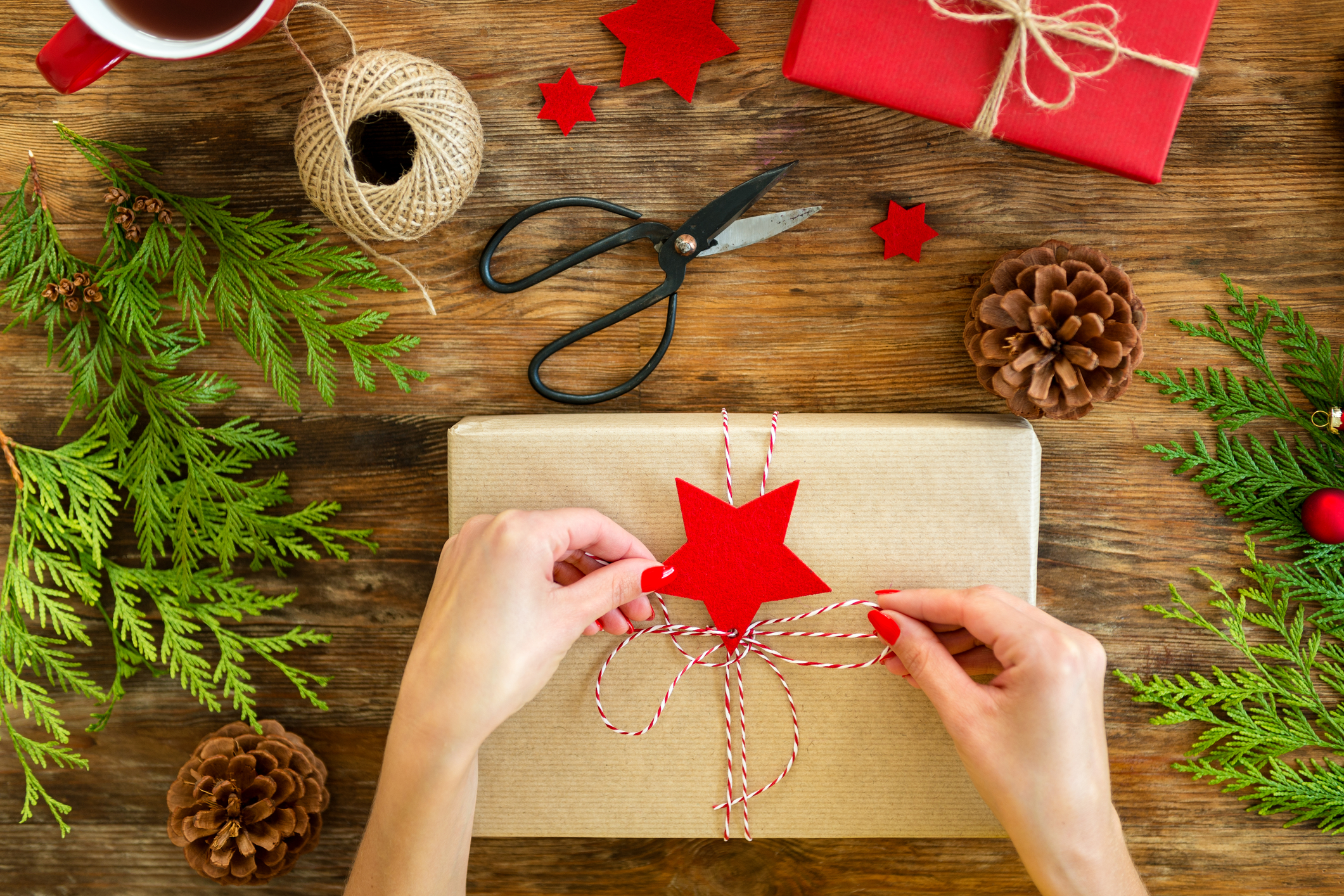 tying a string bow on a gift wrapped in craft paper.
