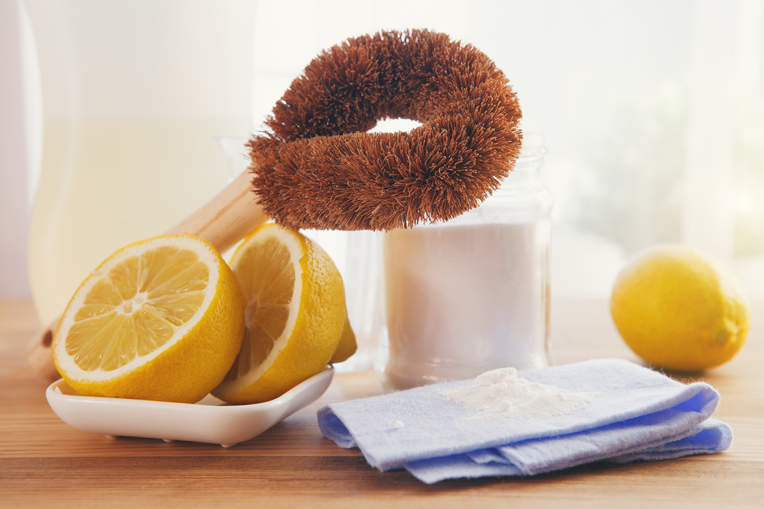 Eco-friendly natural cleaning products, bamboo brush, lemon, baking soda sodium bicarbonate on wooden table.