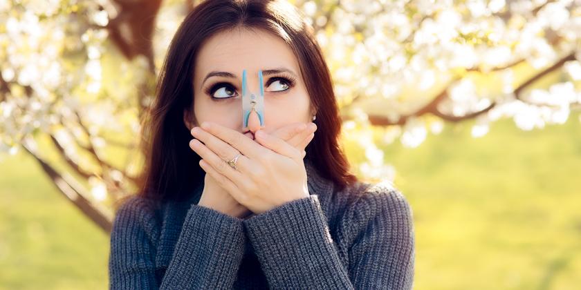 a woman pinching her nose and covering her mouth to avoid seasonal allergies