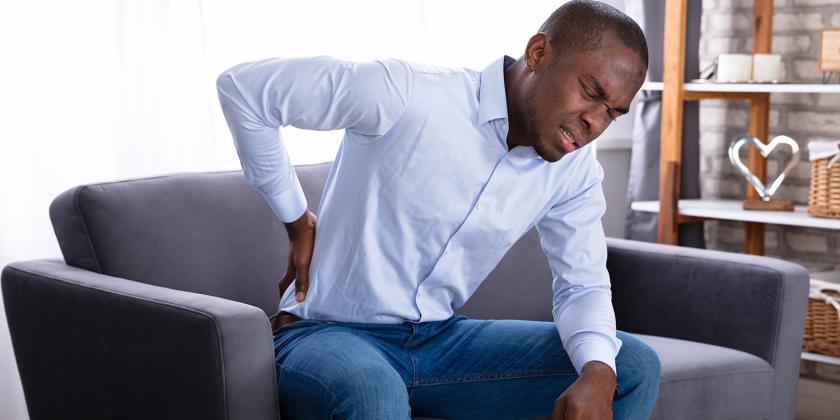 a man holding his aching back in pain