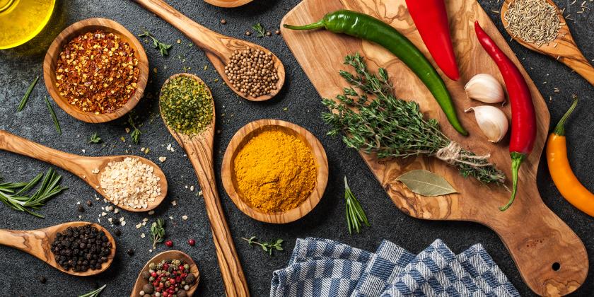 A cooking table with healthy vegetables, herbs, and spices
