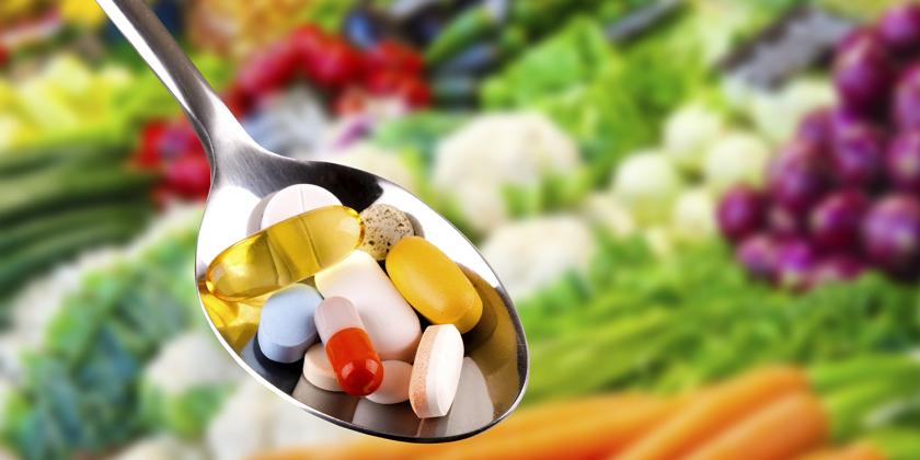 a spoonful of all-natural supplements with fresh produce in the background