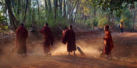 young monks sweeping the dirt yard