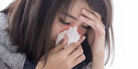 Allergies are Linked to Anxiety a stressed woman sneezing into a tissue
