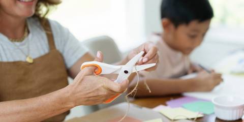 a mother using scissors to help her child with a craft project