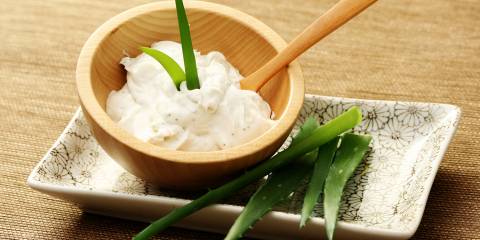 a bowl of aloe cream and stems from the aloe vera plant
