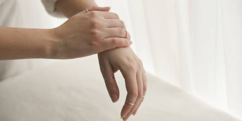 a woman in a sweater rubbing ointment on her hands