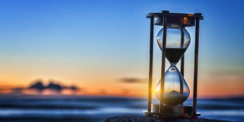 sunset shining through an hourglass on the beach