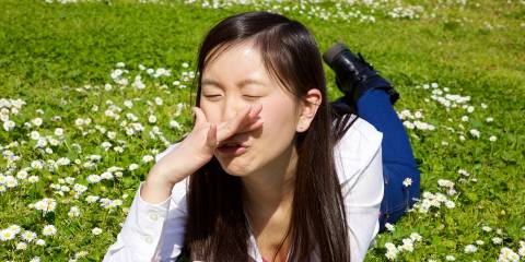 Allergy-Fighting Foods and Tea a young Asian girl sneezing in a field of clover