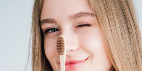 a girl holding a bamboo toothbrush