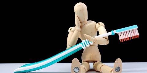 Herbs for Natural Oral Care a wooden figure with a toothache and a giant brush