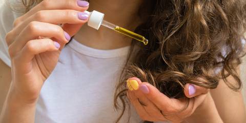 Natural Beauty: Beneficial Oils for Hair and Skin a young woman applying oil to her hair