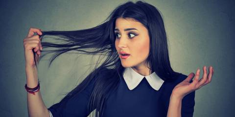 Natural Help for Thinning Hair A surprised young woman holding her thinning hair