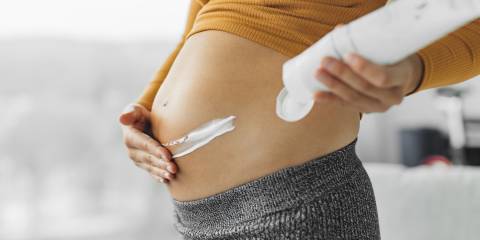 a pregnant woman applying cream to help with stretch marks