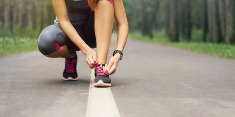 A woman tying her shoe in preparation for a run.