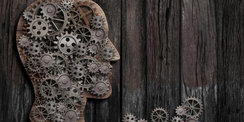 A wooden cut-out of a head with interlocking gears inside it