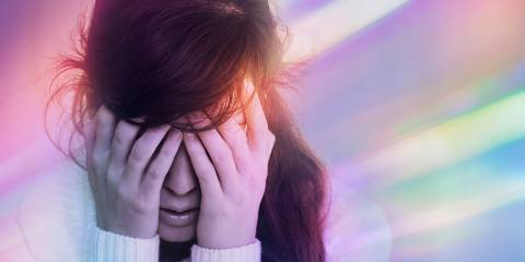 a dizzy woman with a headache, bathed in colored light