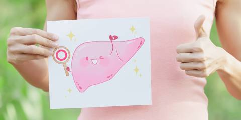 a woman holding a cartoon illustration of a happy, healthy liver