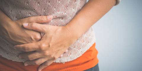 A woman holding stomach with bloating discomfort.