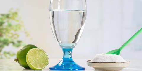 Natural Ways to Soothe the Burn of Acid Reflux A glass of water, a sliced lime and a small dish of baking soda with a green spoon in it.
