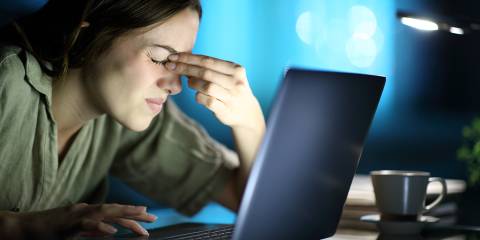 a woman straining her eyes at night looking at a screen