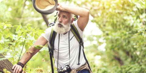 a healthy-looking man feeling exhausted on a hike in the woods