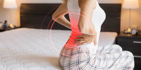 a woman getting out of bed but her back already hurts