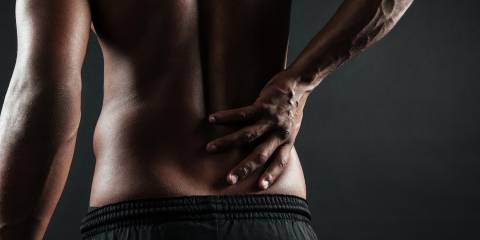 View of a man from the back, holding his back with fibromyalgia pain.
